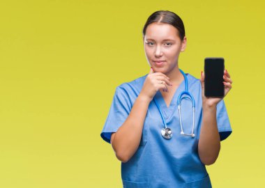 Genç beyaz doktor kadını gösteren smarpthone izole arka plan ciddi bir yüz düşünme hakkında soru, çok karışık bir fikir üzerinde