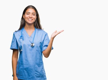 Genç Arap Doktor cerrah kadın neşeli sunulması ve kameraya bakarak avucunun ile işaret gülümseyen izole arka plan.