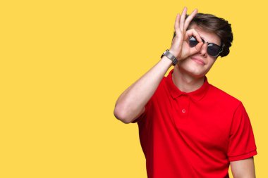 Yakışıklı delikanlı gülümseyen, parmakları ile mutlu yüz üzerinden seyir göz el ile ok jest yapıyor izole arka plan üzerinde güneş gözlüğü takıyor.