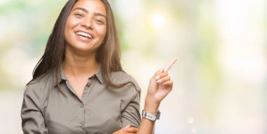 Yüzünde kocaman bir gülümseme ile izole arka plan üzerinde genç güzel Arap kadın kameraya bakarak yan el ve parmak ile işaret.