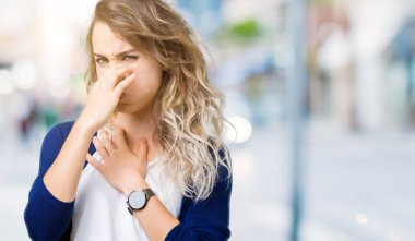 Güzel sarışın genç kadın bir şey pis ve iğrenç kokulu izole arka plan, dayanılmaz koku, holding nefes burun parmaklar ile. Kötü kokuyor kavramı.