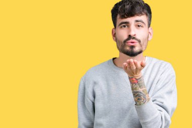 Bir öpücük el ile güzel ve seksi olmak hava üfleme kamera bakarak izole arka plan üzerinde sweatshirt giyen genç yakışıklı adam. Aşk ifade.
