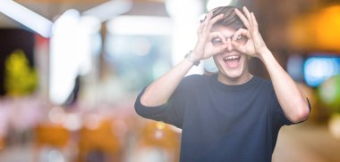 Dilini, parmaklarının arasından baktığını yapışmasını dürbün gibi ok jest yapıyor izole arka plan üzerinde gözlük takan yakışıklı delikanlı. Deli ifade.