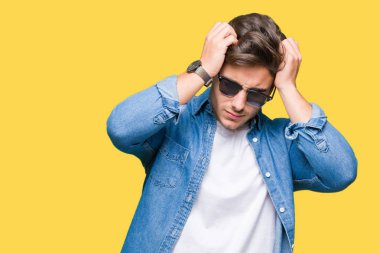 Yakışıklı delikanlı çünkü umutsuz ve stresli baş ağrısı acı izole arka plan üzerinde güneş gözlüğü takıyor ağrı ve migren. Ellerini kafasına.