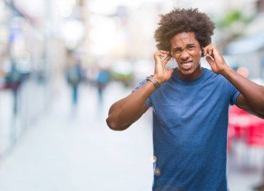 Yüksek sesle müzik gürültü rahatsız ifade parmaklarıyla kulaklarıyla kapsayan izole arka plan üzerinde Afro Amerikalı adam. Sağır kavramı.