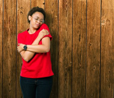 Güzel genç Afro-Amerikan kadın gözlük izole üzerinde emin gülümseyen Hugging kendini mutlu ve olumlu, arka plan. Kendi aşk ve öz bakım