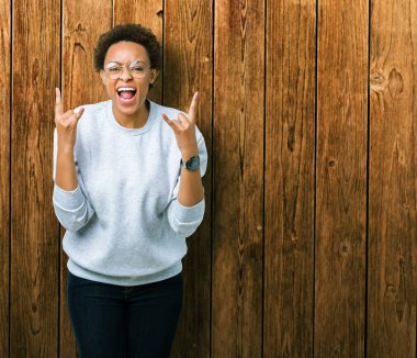 Deli ifade rock simge elle yapıyor ile bağırarak izole arka plan üzerinde gözlük takan genç güzel Afrikalı-Amerikalı kadın. Müzik yıldızı. Ağır kavramı.