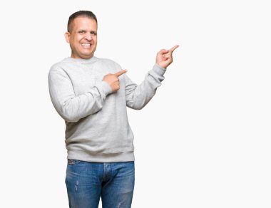 Hayret ve el ile sunulması ve parmak ile işaret ederken kameraya gülümseyen izole arka plan üzerinde spor kazak giyen orta yaş Arap adam.