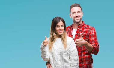 Genç çift aşık hareketi el ile mutlu yaşasın yapıyor izole arka plan üzerinde kış kazak giyiyor. Kameraya bakarak başarı gösteren ile ifade onaylama.