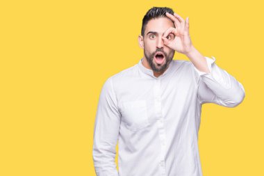 Sürpriz yüz, göz parmaklarının arasından seyir ile genç iş adamı ok jest yapıyor izole arka plan üzerinde şok. İmansız ifade.