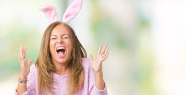 Orta yaş esmer kadın deli ve silah ile başarı için deli kutluyor izole arka plan üzerinde Paskalya tavşan kulakları giyen kaldırdı ve heyecanlı çığlık gözler kapalı. Kazanan kavramı