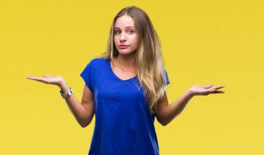 Genç güzel sarışın kadın izole arka plan clueless ve şaşkın bir ifadeyle kollar ve eller kaldırdı. Şüphe kavramı.