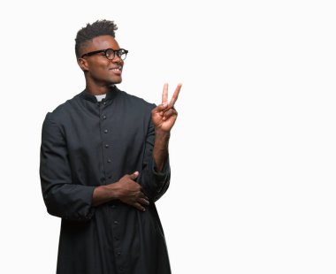 Mutlu yüz zafer işareti yaparken kameraya göz kırpıyor ile gülümseyen izole arka plan genç Afro-Amerikan rahip adam. İki numaralı.