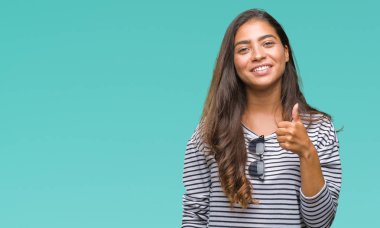 Genç güzel Arap kadın hareketi el ile mutlu yaşasın yapıyor izole arka plan üzerinde güneş gözlüğü takıyor. Kameraya bakarak başarı gösteren ile ifade onaylama.