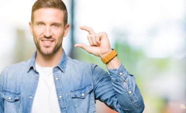 Sakal denim ceket gülümseyen ve boyutu işaret parmaklı ararken ve kamera işi el ile kendinden emin eller ve mavi gözlü yakışıklı adam. Ölçü kavramı.