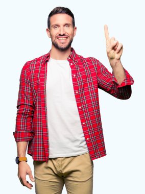 Yakışıklı adam rahat gömlek gösterme ve kendinden emin ve mutlu gülümseyen bir parmak ile işaret eden oktan yukarı giyiyor.