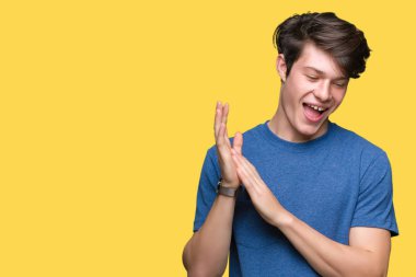 Mavi t-shirt üzerinde izole giyen genç yakışıklı adam arka plan Clapping ve mutlu ve neşeli, gururlu gülümseyen birlikte eller alkış