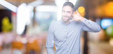 Yakışıklı delikanlı yapıyor gülümseyen izole arka plan üzerinde telefon hareketi ile el ve parmak telefonda konuşuyor gibi. Kavramları iletişim.