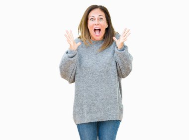 Üzerinde kış kazak giyen güzel orta yaş kadın deli kutluyor arka plan izole ve başarı için kaldırdı kollarını açarak hayrete ve heyecanlı çığlık gözleri açık. Kazanan kavramı
