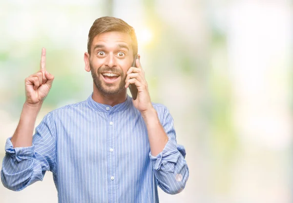 Young handsome man speaking on the phone over isolated background surprised with an idea or question pointing finger with happy face, number one