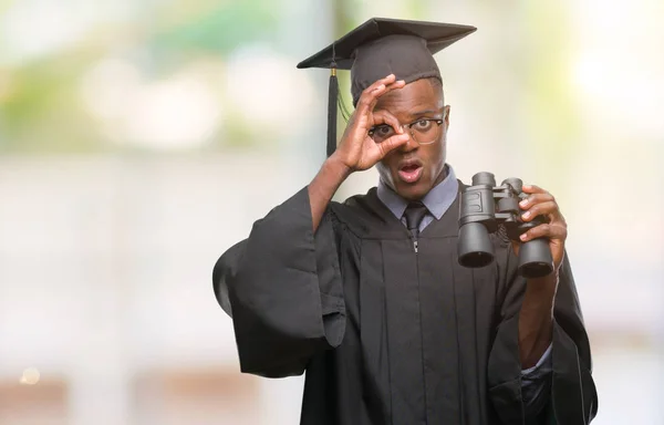 ヤング卒業したアフリカ系アメリカ人の男が指を通して見る目に手で サインをして笑っている幸せそうな顔で双眼鏡を使用して仕事を探して — ストック写真