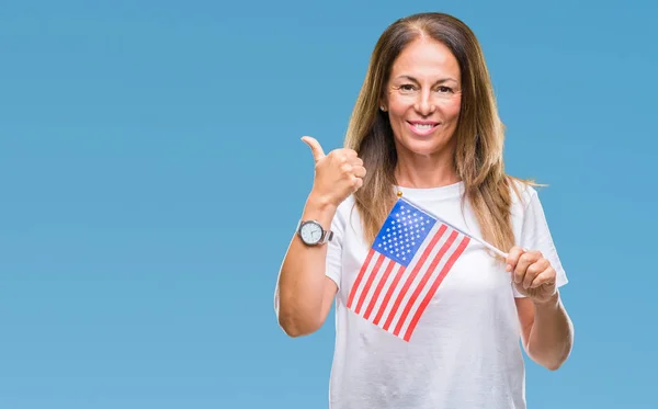 Middle age hispanic woman holding flag of United States of America over isolated background happy with big smile doing ok sign, thumb up with fingers, excellent sign
