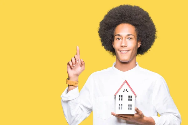 Joven Afroamericano Hombre Con Afro Cabello Celebración Casa Sorprendido Con —  Fotos de Stock