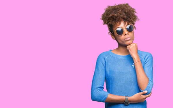 stock image Beautiful young african american woman wearing sunglasses over isolated background with hand on chin thinking about question, pensive expression. Smiling with thoughtful face. Doubt concept.