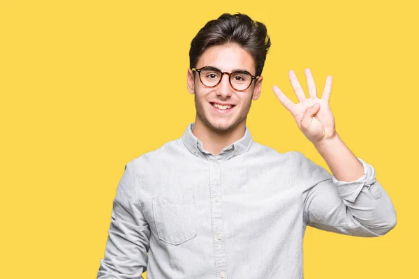 年轻的帅哥戴着眼镜在孤立的背景显示和手指第四 而微笑着自信和快乐 — 图库照片