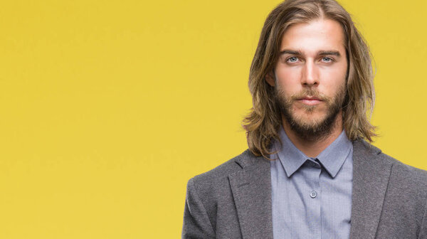 Young handsome business man with long hair over isolated background with serious expression on face. Simple and natural looking at the camera.