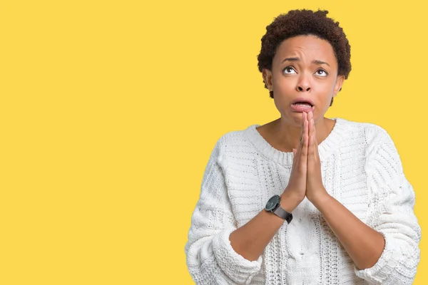 Beautiful young african american woman wearing sweater over isolated background begging and praying with hands together with hope expression on face very emotional and worried. Asking for forgiveness. Religion concept.