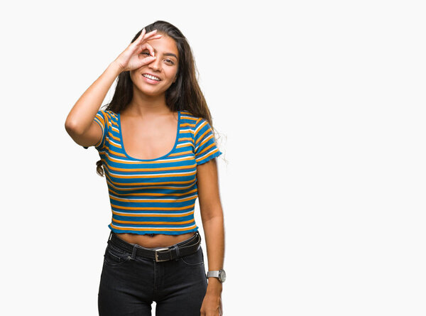 Молодая красивая арабская женщина на изолированном фоне делает хорошо жест с рукой улыбается, глаза смотрят сквозь пальцы с счастливым лицом
.