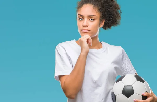 年轻美丽的非洲裔美国人拿着足球在孤立的背景下严重的脸思考问题 很困惑的想法 — 图库照片