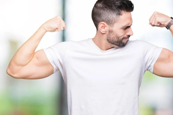 Jovem Vestindo Camiseta Branca Casual Sobre Fundo Isolado Mostrando Músculos — Fotografia de Stock