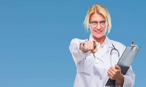 Middle age blonde doctor woman holding clipboard over isolated background pointing with finger to the camera and to you, hand sign, positive and confident gesture from the front