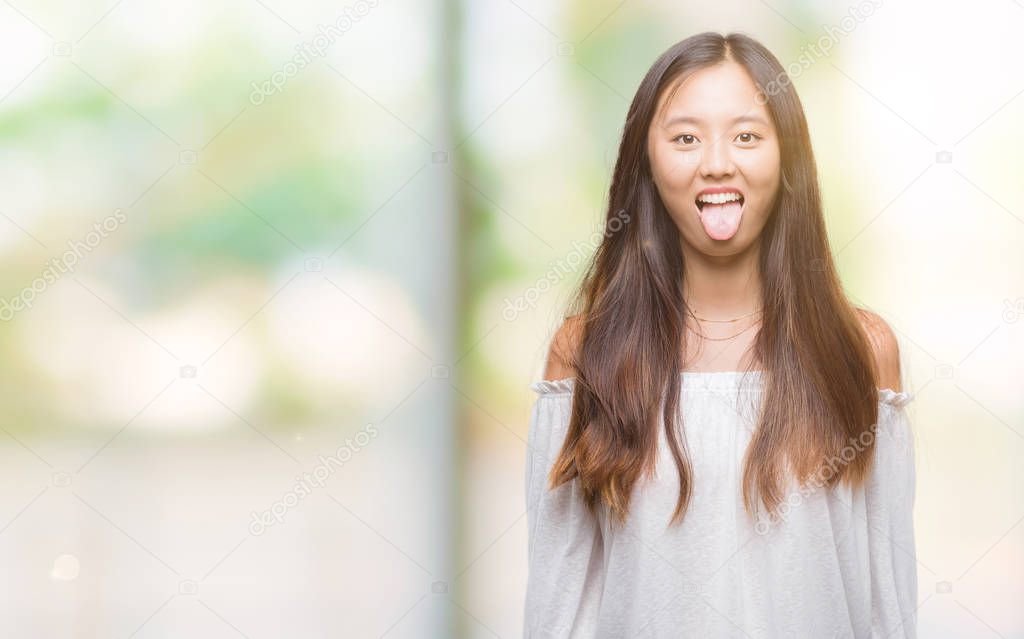 Young asian woman over isolated background sticking tongue out happy with funny expression. Emotion concept.