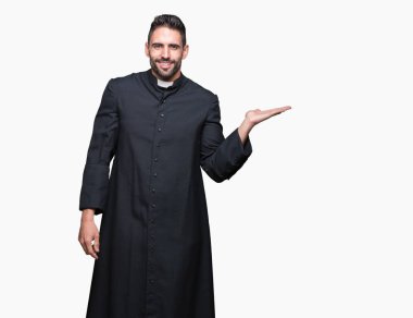 Genç Hıristiyan rahip neşeli sunulması ve kameraya bakarak avucunun ile işaret gülümseyen izole arka plan üzerinde.