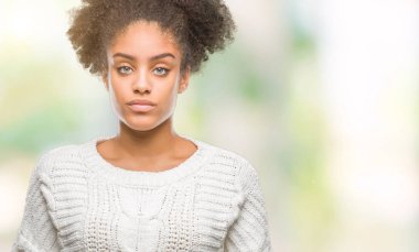 Yüzünde ciddi bir ifade ile izole arka plan üzerinde kış kazak giyen genç afro Amerikalı kadın. Basit ve doğal kameraya bakıyor.