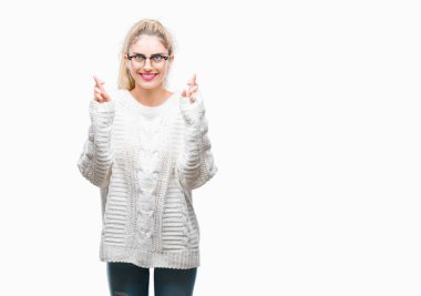 Umut ve gözleri kapalı geçiş parmaklarıyla gülümseyen izole arka plan üzerinde gözlük takan genç güzel sarışın kadın. Şans ve batıl kavramı.