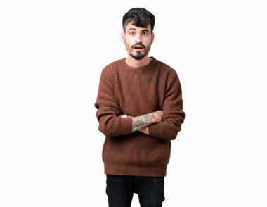 Korkuyor ve şok sürpriz ifade, korku ve heyecan yüz ile izole arka plan üzerinde kış kazak giyen genç yakışıklı adam.