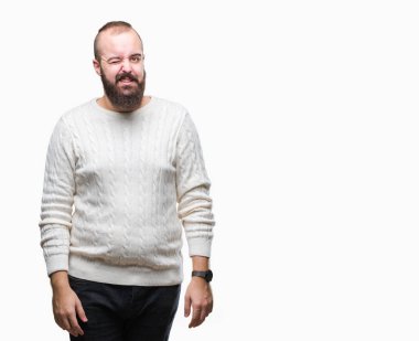 Seksi bir ifadeyle, neşeli ve mutlu yüzünü kameraya bakarak göz kırpıyor izole arka plan üzerinde kış kazak giyen genç beyaz hipster adam.