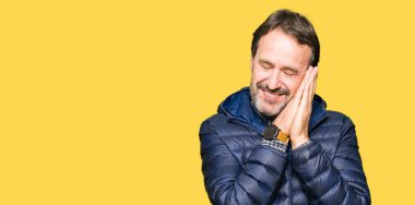 Orta yaş yakışıklı adamın kış ceket uyku giydiğini hayal ve elleri ile kapalı gözler gülümseyen birlikte poz yorgun.