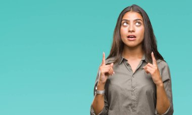 Genç güzel Arap kadın üzerinden hayran ve yukarıya bakıyor ve parmakları ile işaret ve silah kaldırdı sürpriz izole arka plan.