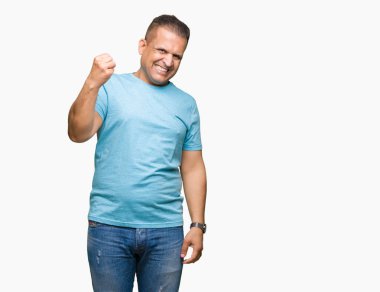 Üzerinde mavi t-shirt giyen orta yaş Arap adam arka plan kızgın izole ve kızgın yetiştirme hayal kırıklığı ve öfke ile bağırarak süre öfkeli yumruk. Öfke ve agresif kavramı.