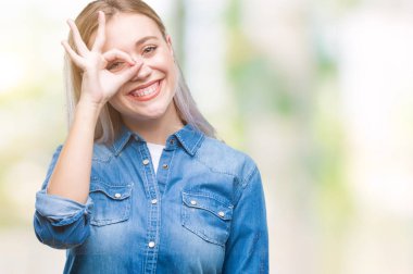 Sarışın genç kadın gülümsüyor, parmakları ile mutlu yüz üzerinden seyir göz el ile ok jest yapıyor izole arka plan üzerinde.