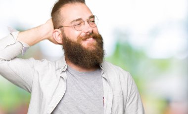 El hareketi ile kendine güvenen dokunaklı saç gülümseyerek, çekici poz gözlüklü genç sarışın adam