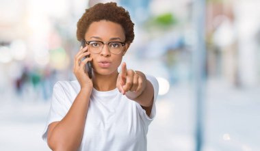 Telefonda konuşmayı genç Afro-Amerikan kadın kamera ve size parmak ile işaret arka plan izole, el işareti, pozitif ve kendinden emin bir jest ön