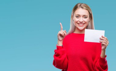 Sarışın genç kadın holding boş kağıt kartı üzerinde arka plan ile bir fikir ya da gülen yüz, bir numara ile parmak işaret soru sürpriz izole