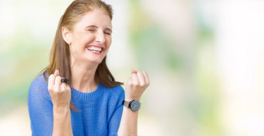 Üzerinde kış kazak giyen güzel orta yaş Olgun kadın gülümseyerek ve başarı için çığlık arka plan çok mutlu ve heyecanlı kaldırdı, silah ile kazanan jest yapıyor izole. Kutlama kavramı.