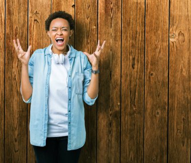 Üzerinde kulaklık giyen genç Afro-Amerikan kadın arka plan deli izole ve deli bağırarak ve agresif ifade ve silah kaldırdı bağırıyor. Hayal kırıklığı kavramı.